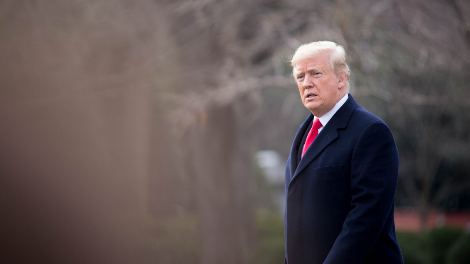 Trump walking in a coat.