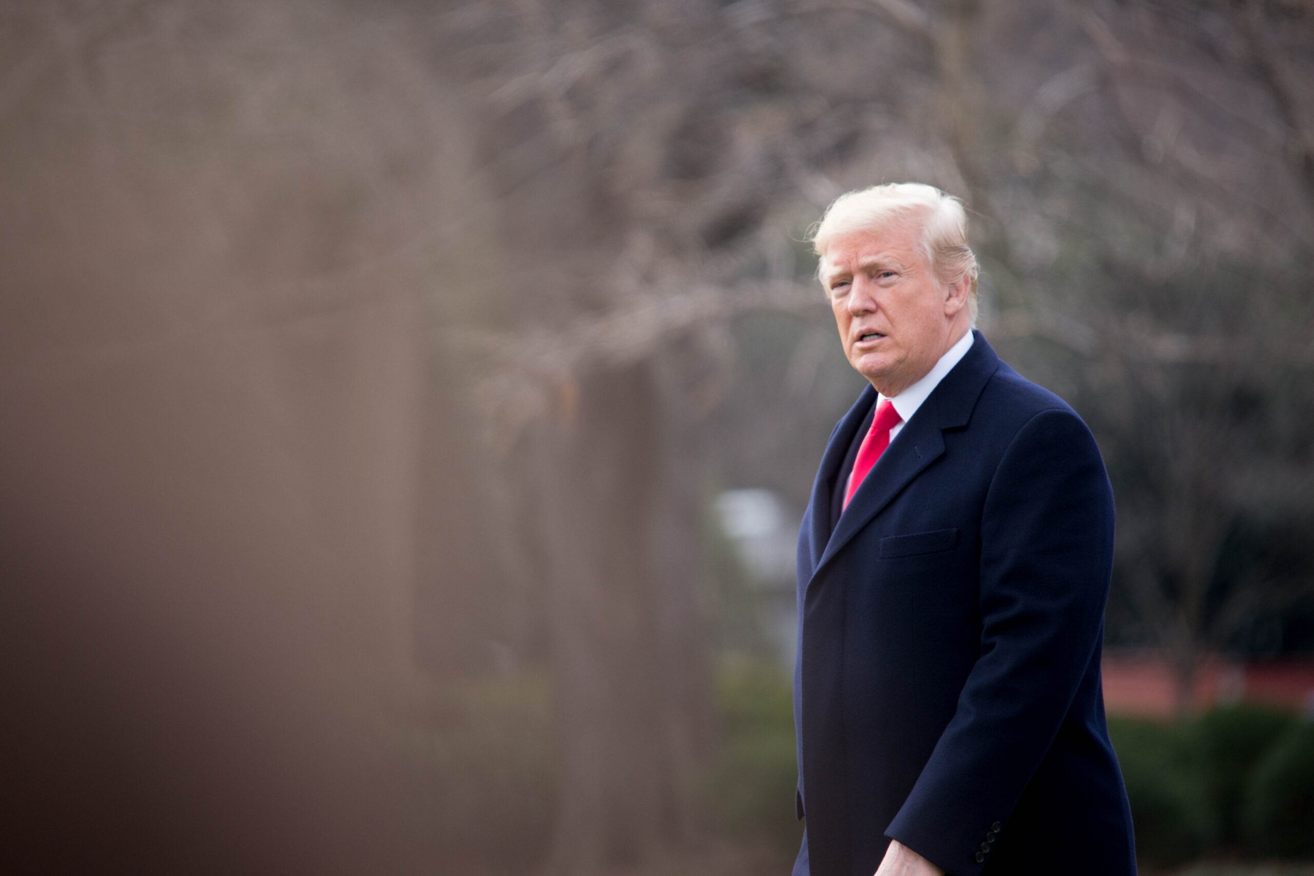 Trump walking in a coat.