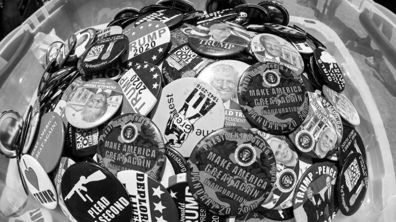 Trump buttons in a pile in black and white.