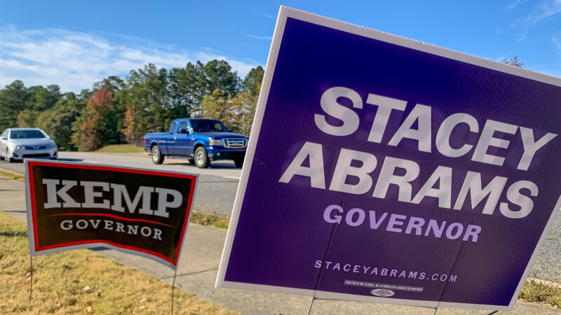 Abrams and Kemp for governor signs on the side of the road.