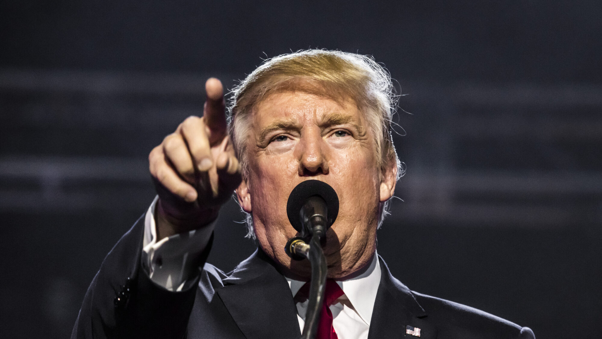 Trump pointing and speaking into a mic.