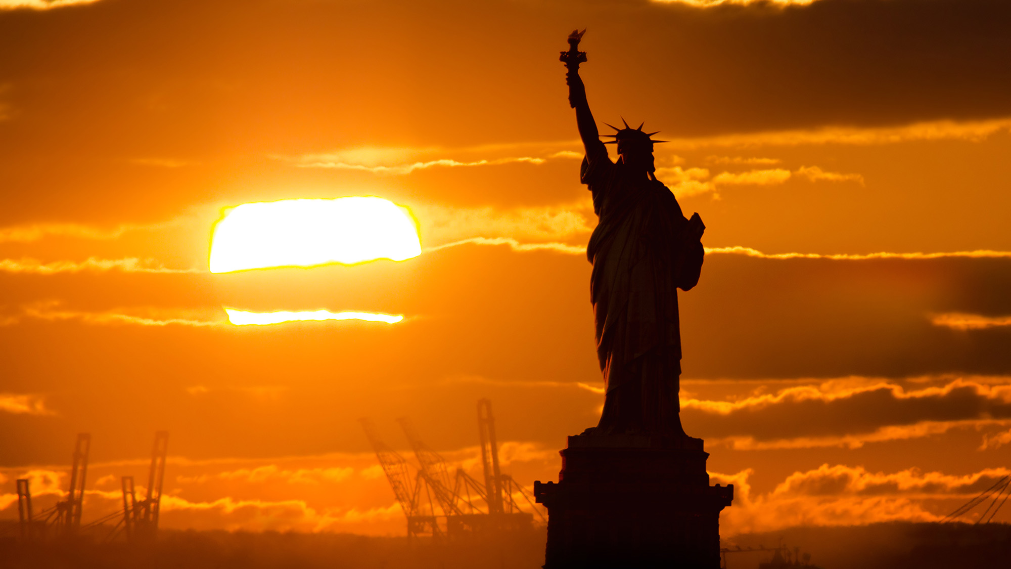 The Statue of Liberty silhouetted against the sunset.