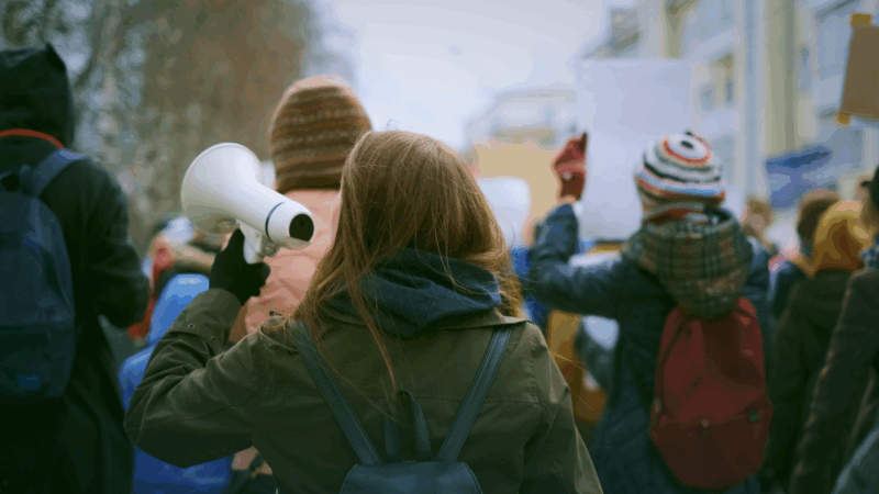 A young activist taking part in a protest from behind.