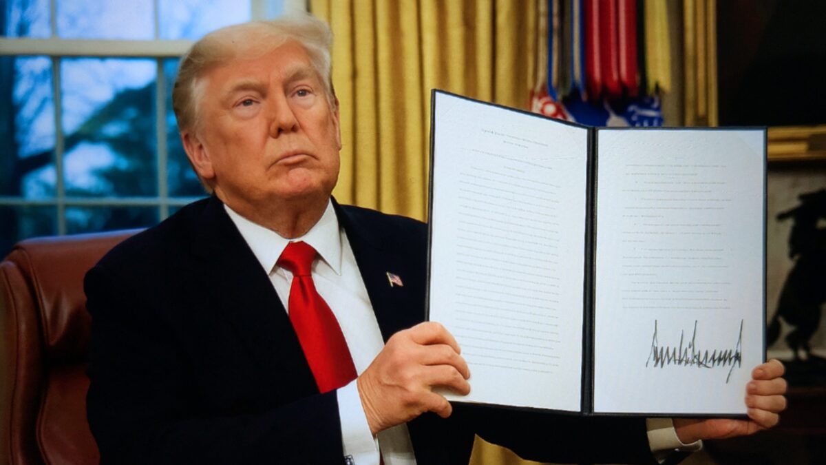 President Trump signing an executive order in the Oval Office.