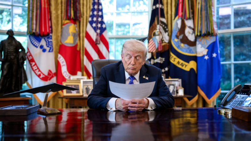 Trump looking at a sheet of paper in the Oval Office.