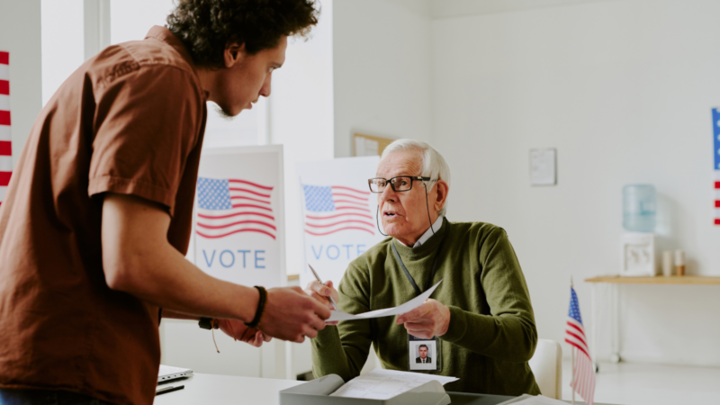 A poll worker helping someone vote.