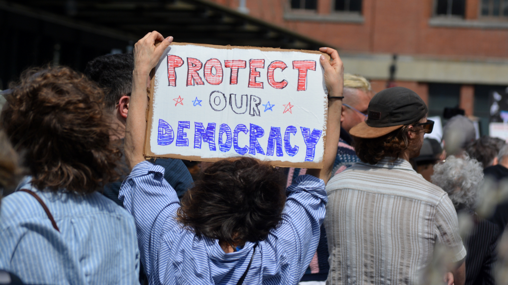 A protester holding up a sign that says "protect our democracy" in New York City,