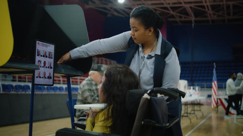 A disabled person working with a poll worker to vote