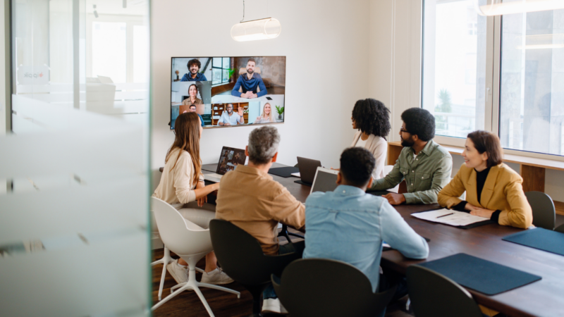 A group in a conference room speaking to people on Zoom.