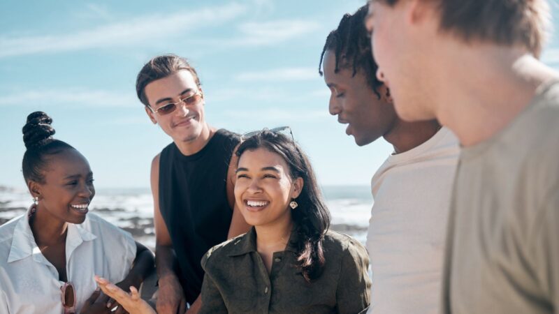 A diverse group of people talking to one another near the ocean.