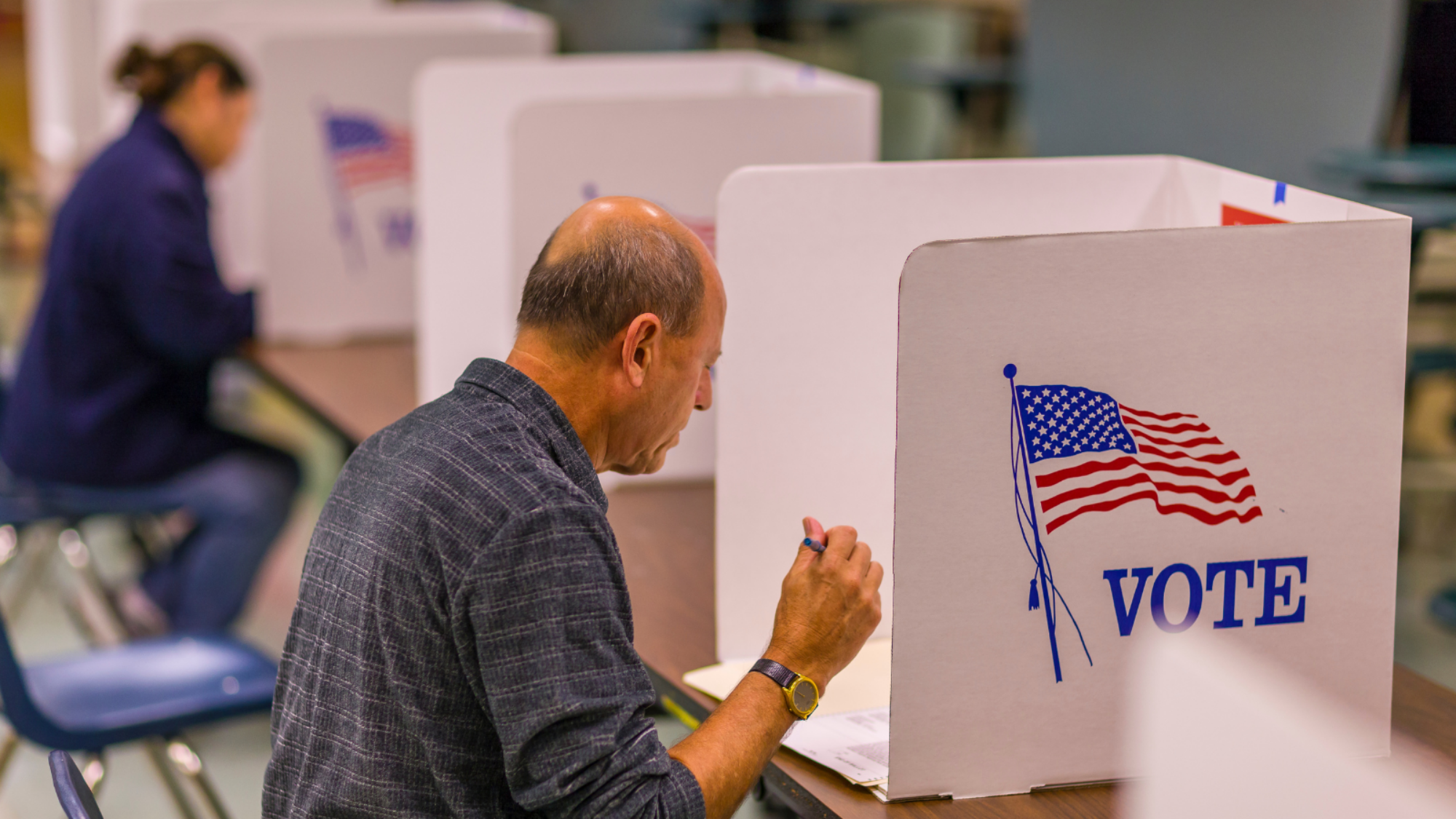A man voting in a seat at a long table