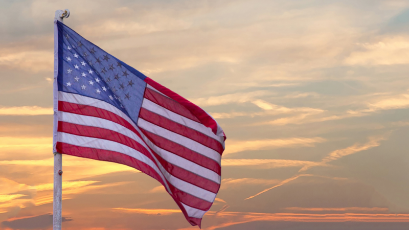 The American flag on a pole against a setting sun.