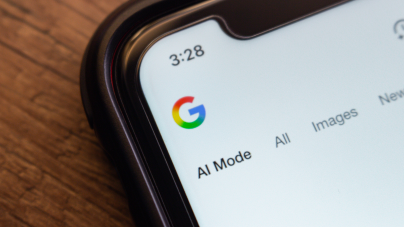 A phone showing Google AI mode on a table.